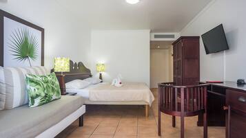 Una habitación de hotel con una cama, un escritorio, una silla, un televisor y una puerta que da a otra habitación.