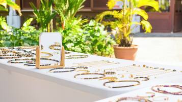 A jewelry display with various necklaces and bracelets on a white table, surrounded by green plants.