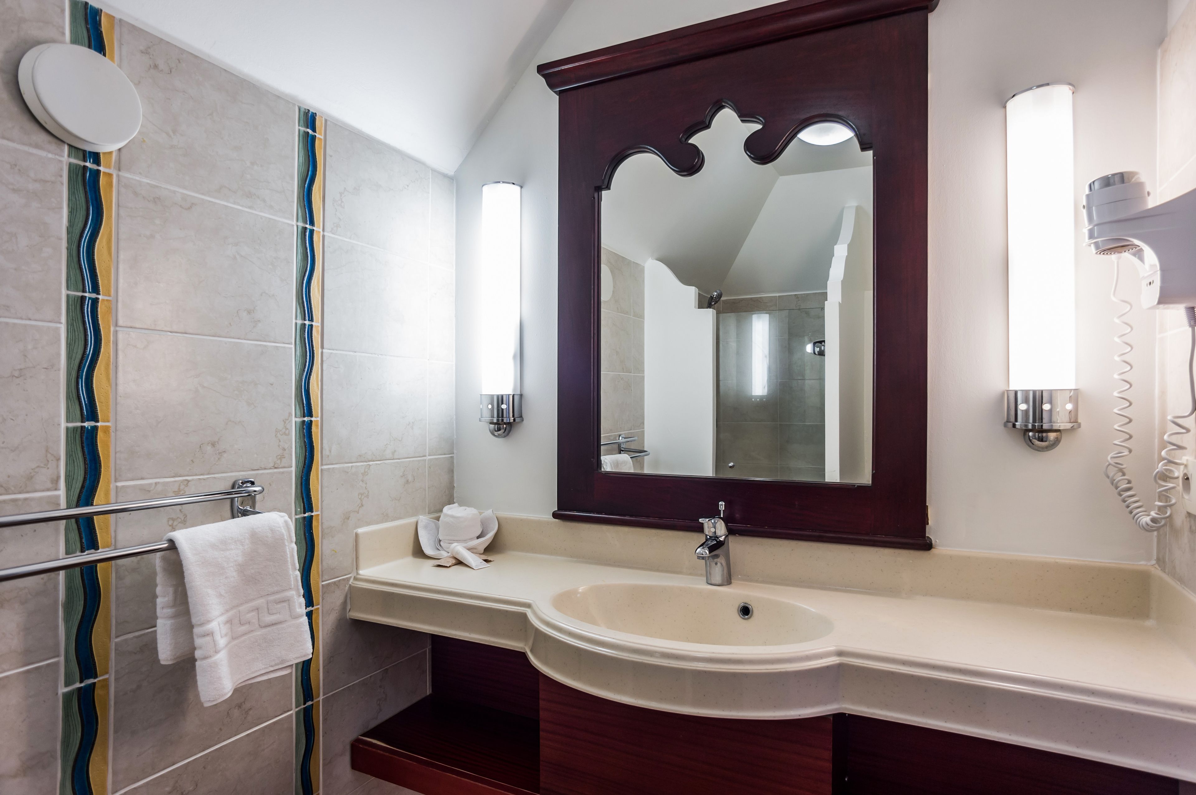 A bathroom with a large mirror, a sink, and a towel rack.