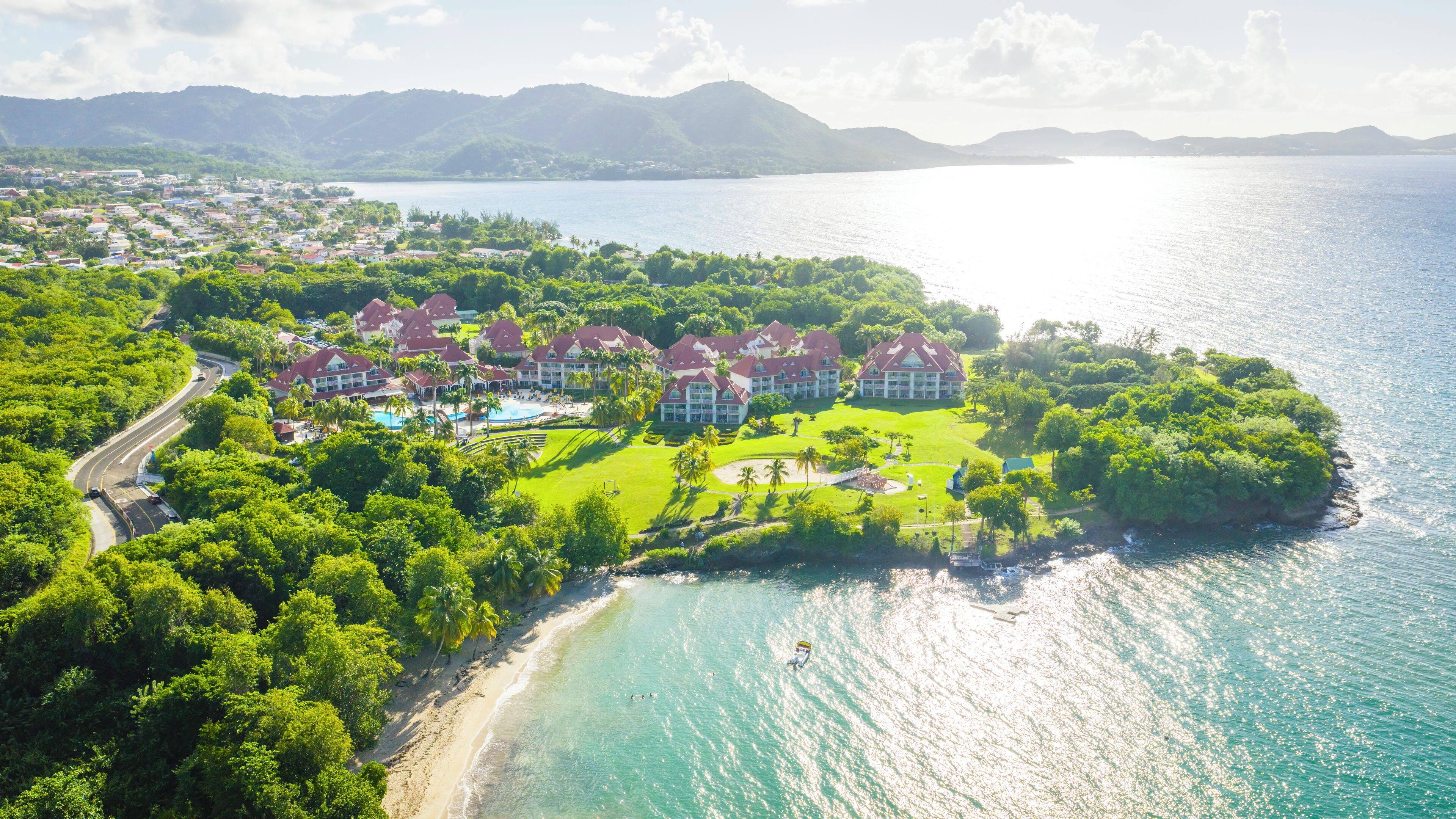 A resort with multiple buildings, a beach, and a large body of water.
