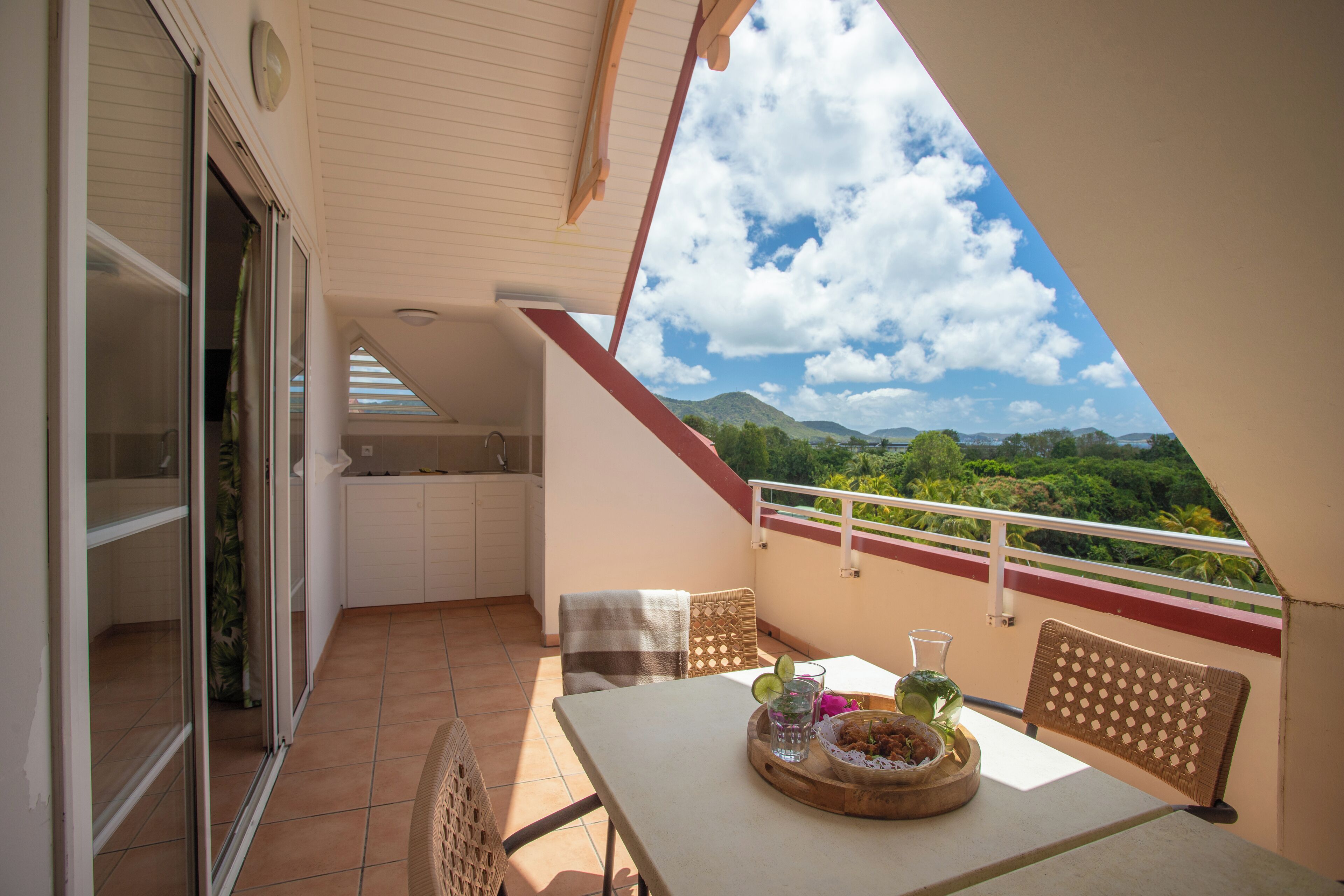 A balcony with a table, chairs, and a view of the mountains.