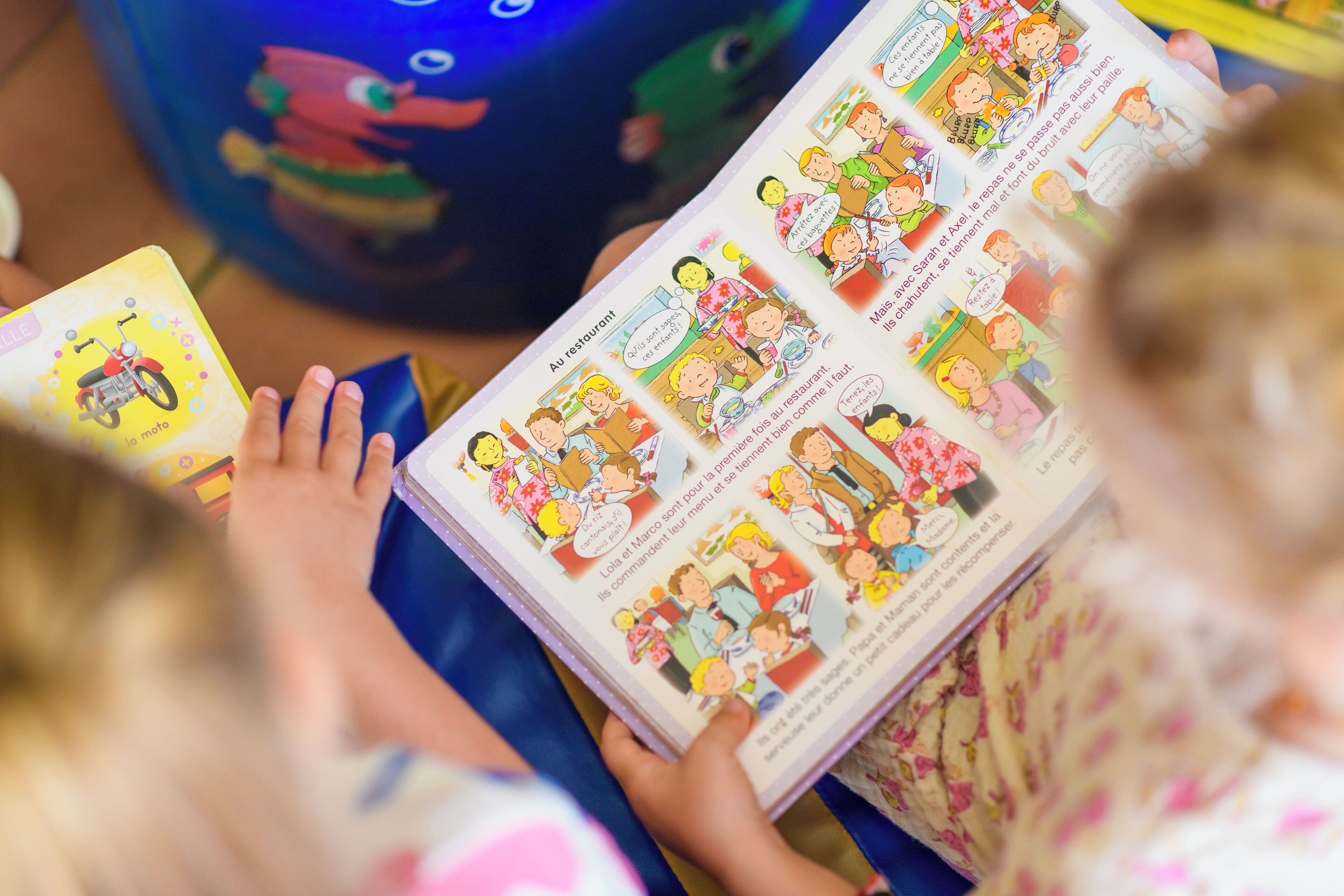 Une personne est en train de lire un livre illustré de dessins colorés.
