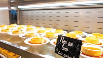Una presentación de postres de flan en recipientes blancos pequeños, dispuestos sobre una barra metálica con un letrero que dice 'Flan au Lard'.