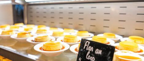 Una presentación de postres de flan en recipientes blancos pequeños, dispuestos sobre una barra metálica con un letrero que dice 'Flan au Lard'.