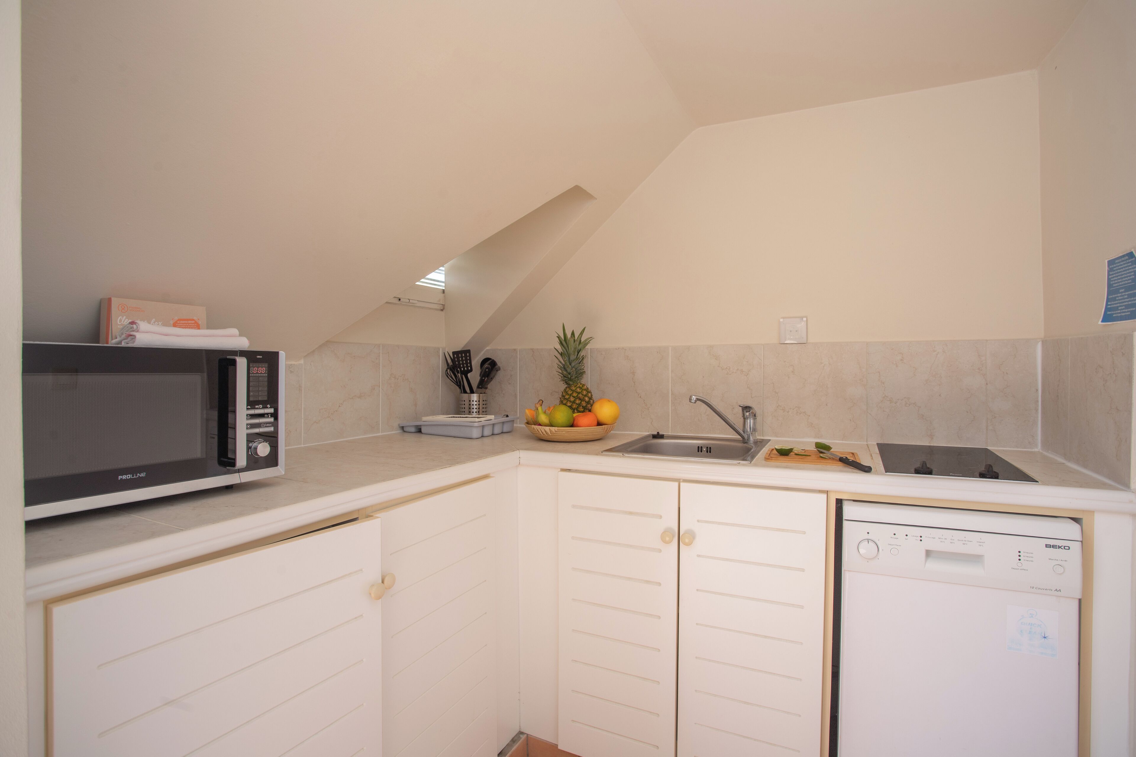 A kitchen with white cabinets, a microwave, a sink, and a dishwashing machine.