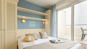 Une chambre à coucher avec un lit, une étagère fixée au mur, une horloge et une vue sur le balcon.
