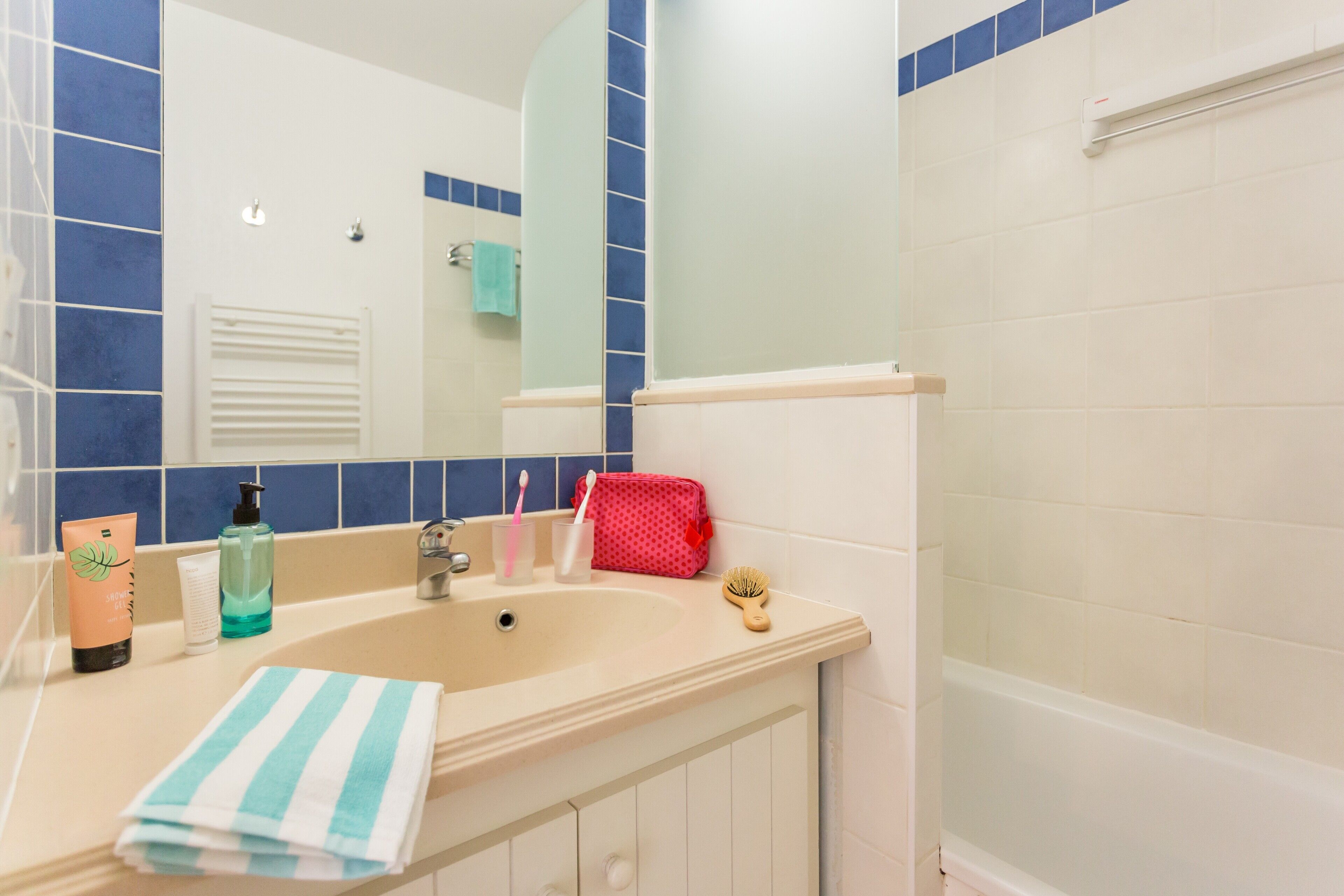 Ein Badezimmer mit Waschbecken, Spiegel und blauen Fliesen.
