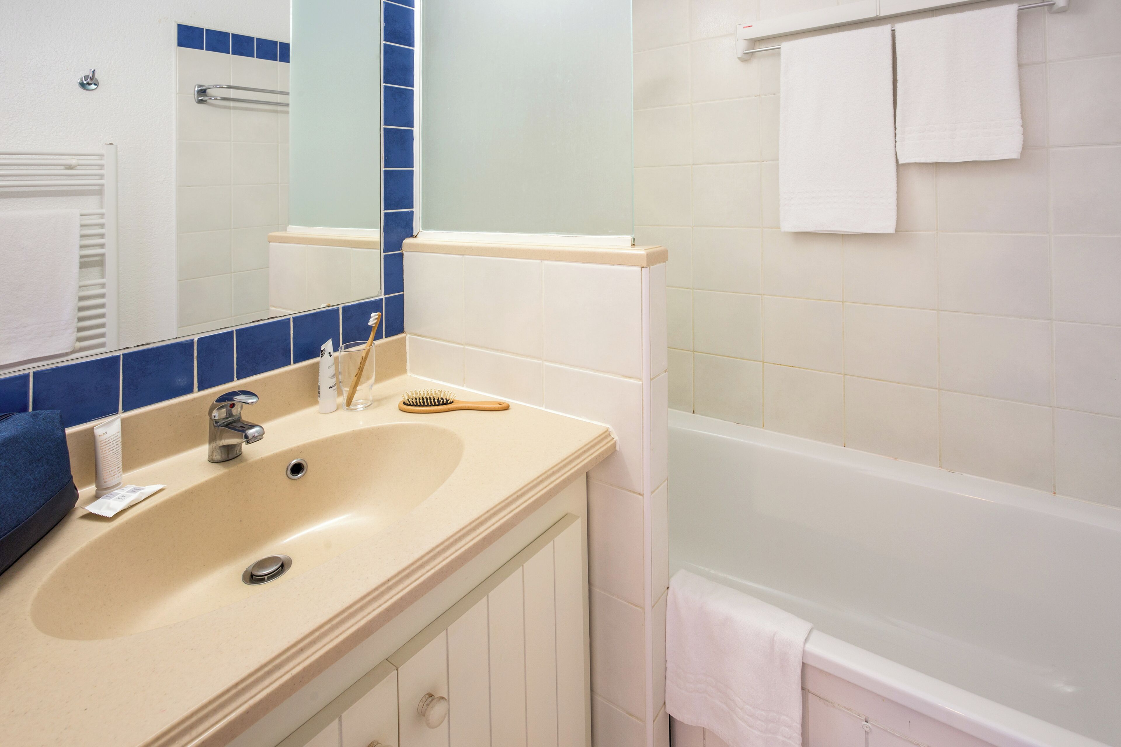 Ein Badezimmer mit Waschbecken, Spiegel und Badewanne.