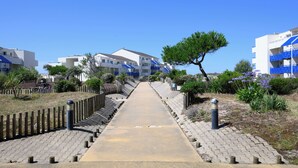 Un chemin menant à un quartier résidentiel, avec des maisons, une clôture en bois et de la verdure.