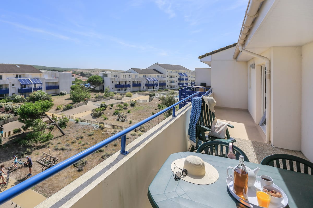 Un balcon avec une table dressée pour le petit-déjeuner, donnant sur un quartier résidentiel composé de plusieurs immeubles.