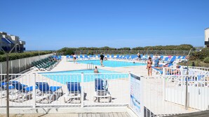 Un espace piscine avec des chaises longues bleues et une piscine.