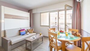 Uma sala de estar moderna com um sofá, uma mesa de jantar com cadeiras e uma janela grande.