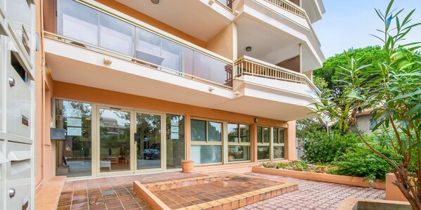 A multi-story hotel with a glass facade, outdoor seating area, and a landscaped garden.