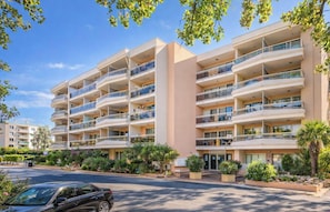 A multi-story hotel with balconies, a parking area, and landscaped gardens. - Pierre & Vacances Résidence Les Platanes (Sainte-Maxime)
