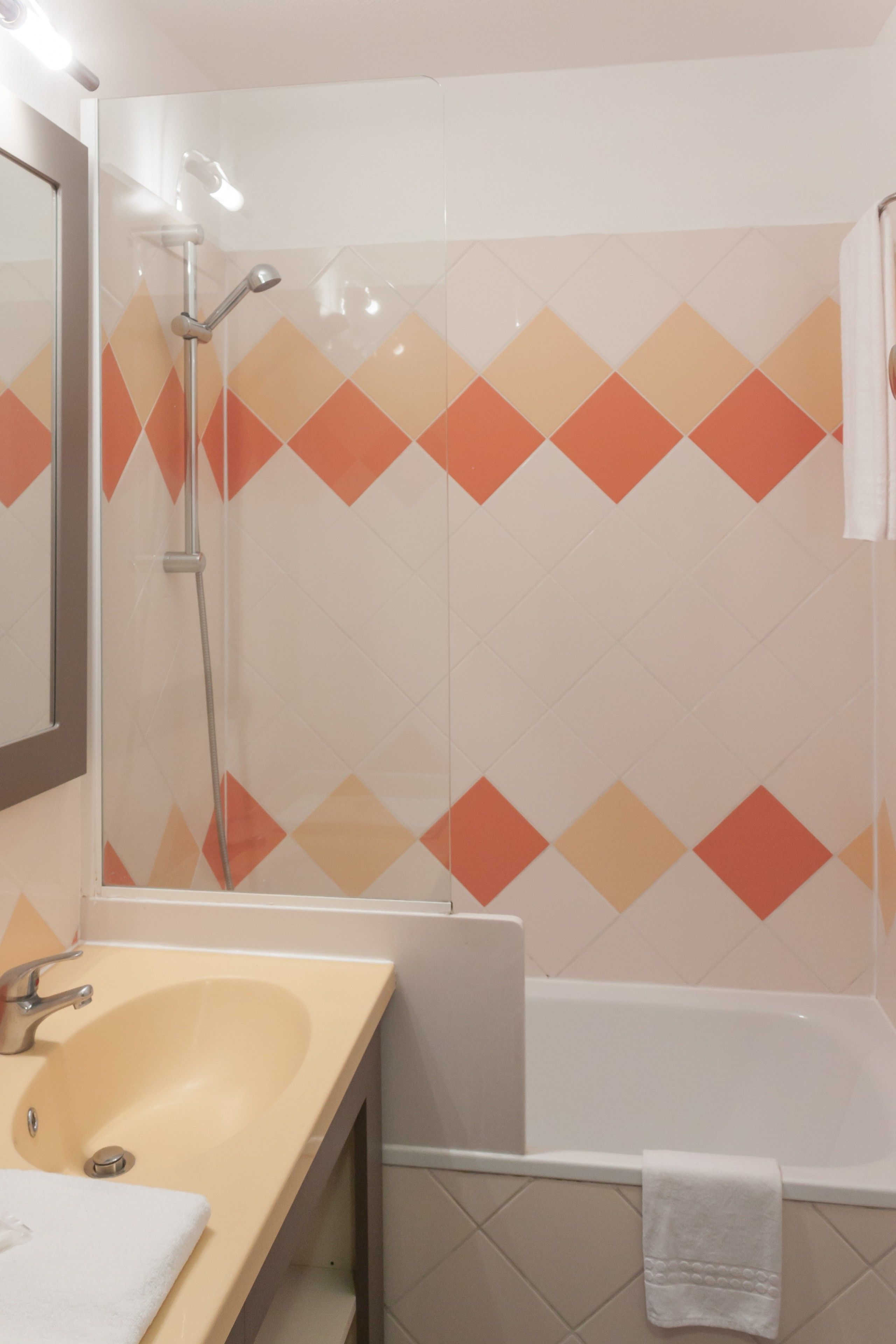 Een badkamer met een wastafel, spiegel, douche en bad.