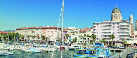 A marina with boats, a blue and yellow boat, and a building with a dome and tower.