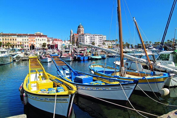 A marina with various boats docked, a prominent building with a dome in the background, and a clear blue sky. - Pierre & Vacances Résidence Promenade des Bains (Saint-Raphael)