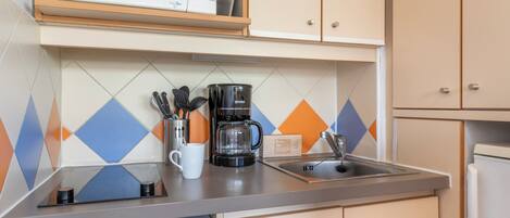 A kitchen with a microwave, coffee maker, and utensils on the counter.