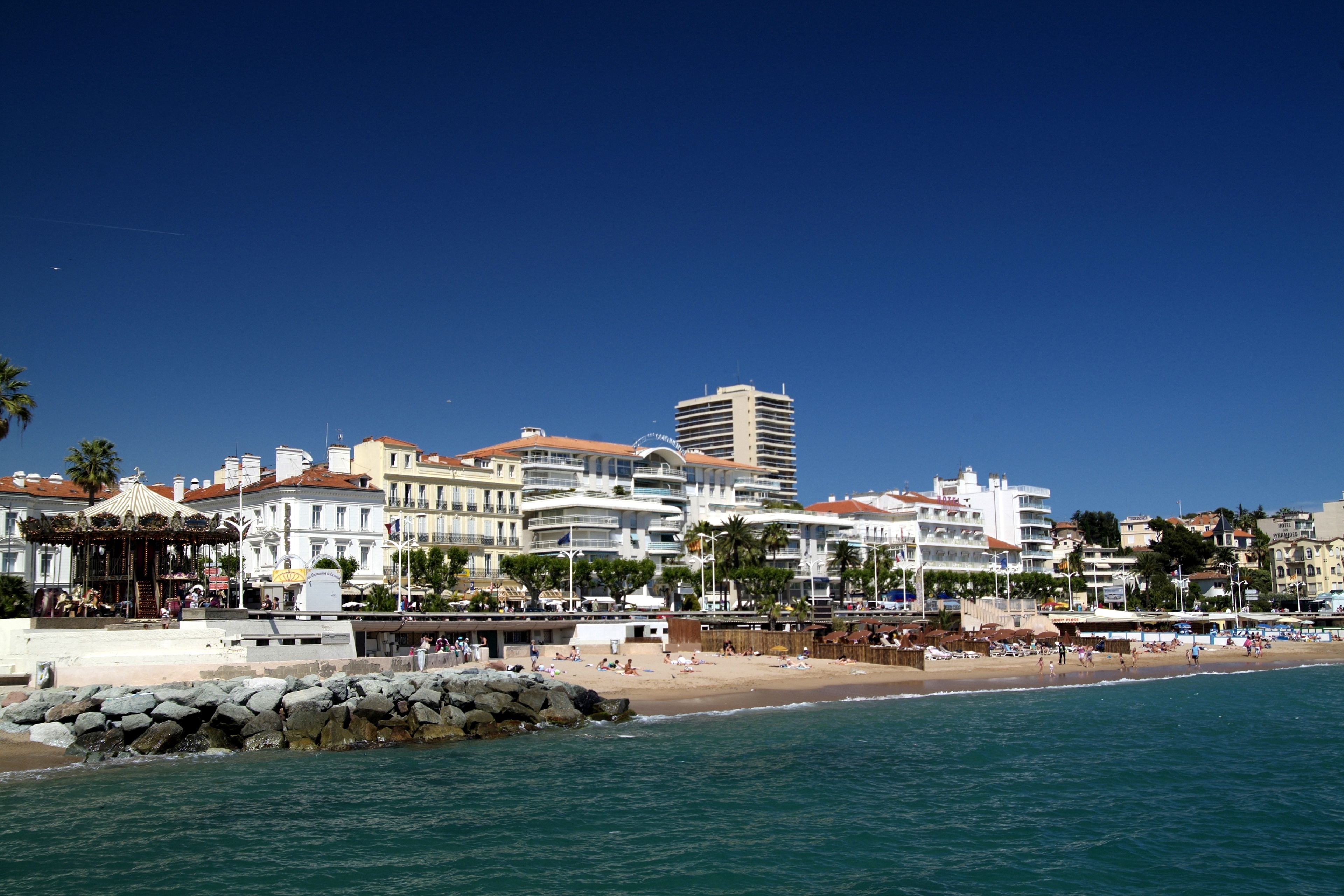 A coastal cityscape with a beach, buildings, and a clear sky.