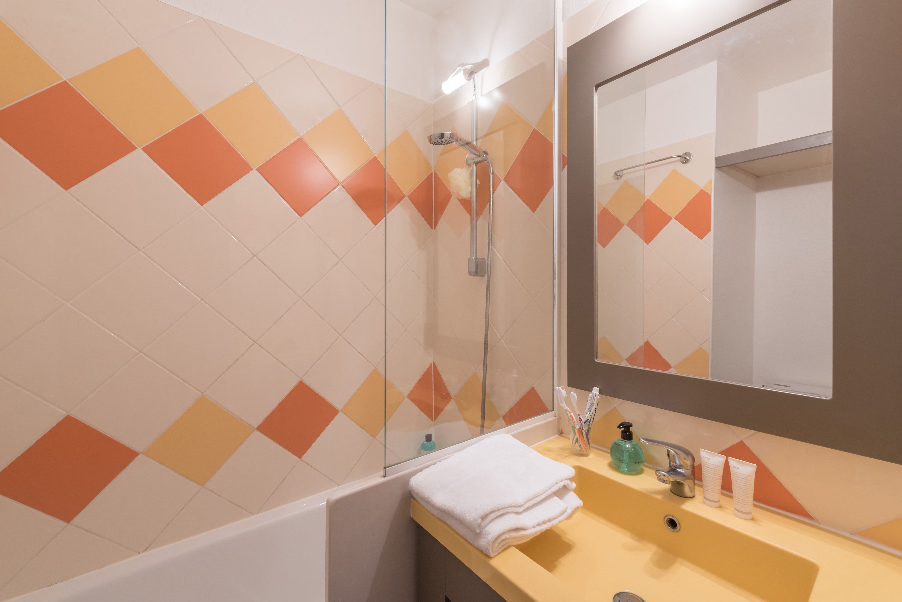 A modern bathroom with a shower, a sink with toiletries, and a mirror.