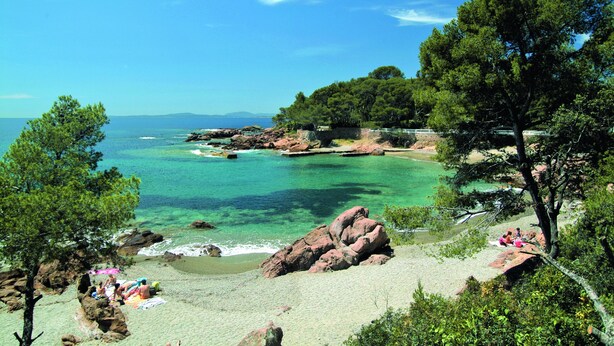 Une plage bordée d’une eau turquoise et limpide, de formations rocheuses et d’une végétation luxuriante.
