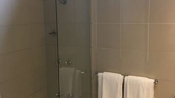 A bathroom with a glass-enclosed shower, a bathtub, and two white towels hanging on a rack.