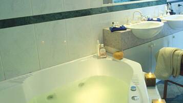 A bathroom with a bathtub, two sinks, and a mirror.