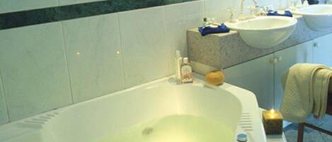 Un baño con bañera, dos lavamanos y un espejo.