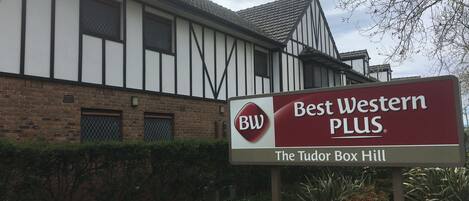 Een bord voor Best Western PLUS hotel met een Tudor Box Hill logo.