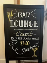 Letrero en una pizarra para un bar-lounge, con letras doradas y blancas, que indica que está abierto todos los días hasta las 2 de la madrugada.