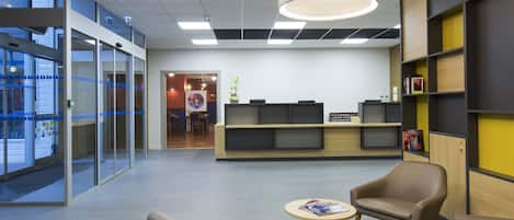 A modern office lobby with glass partitions, a reception desk, and seating areas.