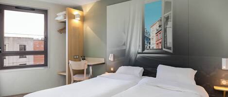 Habitación de hotel con dos camas, un escritorio y una silla.
