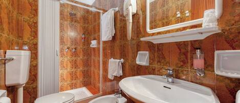 A bathroom with a toilet, bidet, sink, and a shower area.
