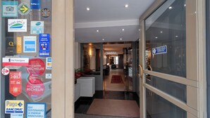 A hotel entrance with a glass door, a reception desk, and a hallway leading to the interior. - Barsotti Hotel (Brindisi)