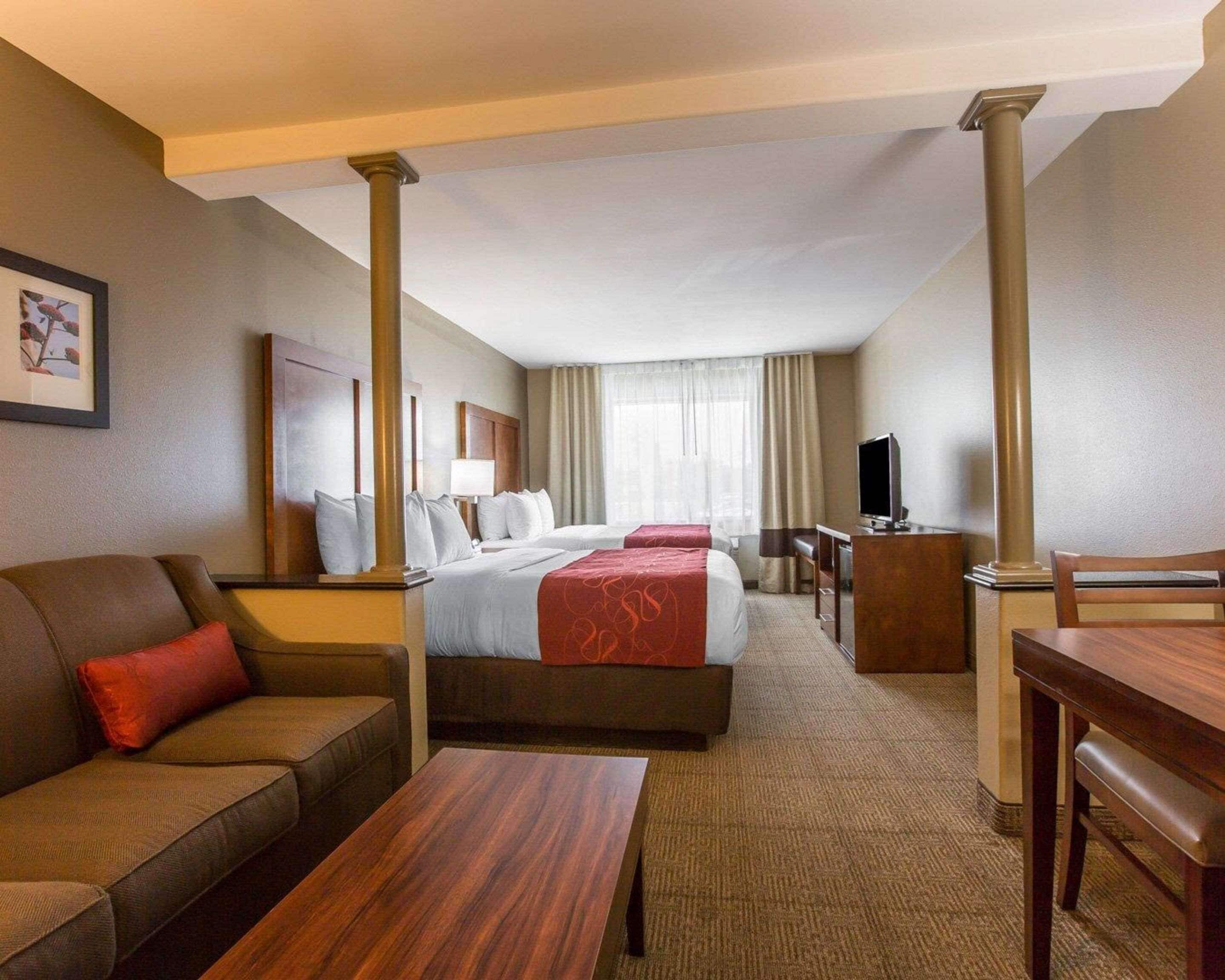 A hotel room with two beds, a sofa, a desk, and a TV.