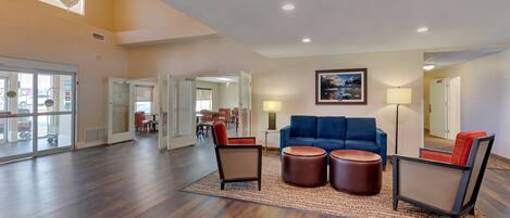 A spacious lobby with a blue sofa, two brown armchairs, and a chandelier.