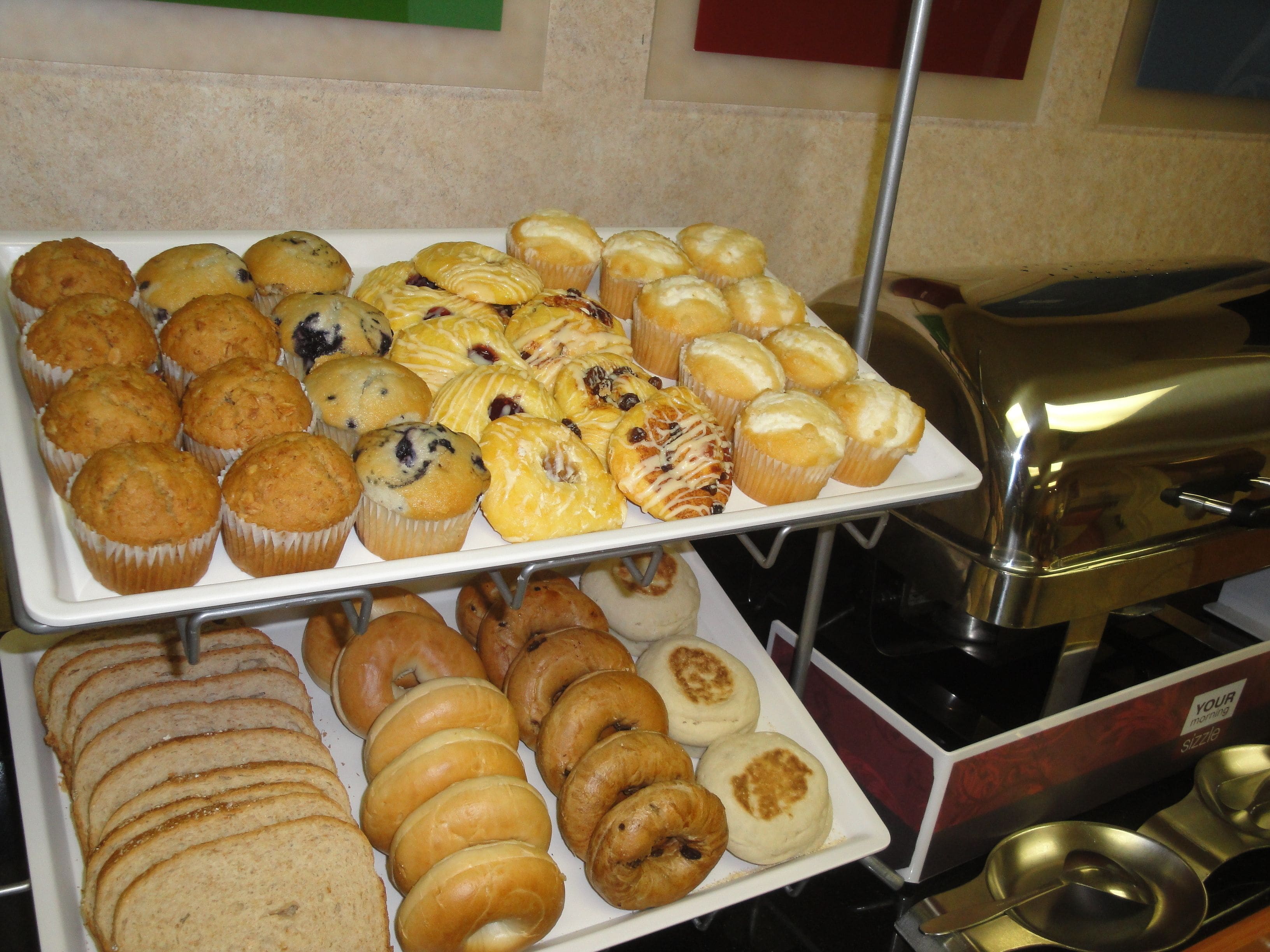 Un bufé con diversos productos horneados, incluyendo muffins, pasteles y bagels.