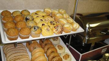 Un bufé con diversos productos horneados, incluyendo muffins, pasteles y bagels.