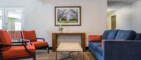 A modern living room with a sofa, chairs, a coffee table, and a framed picture on the wall.