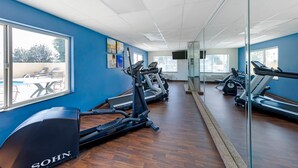 Un gimnasio con equipo de ejercicio, ventanas amplias y vistas al exterior.