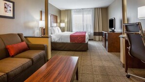 Habitación de hotel con cama, sofá, escritorio, televisor y una silla.