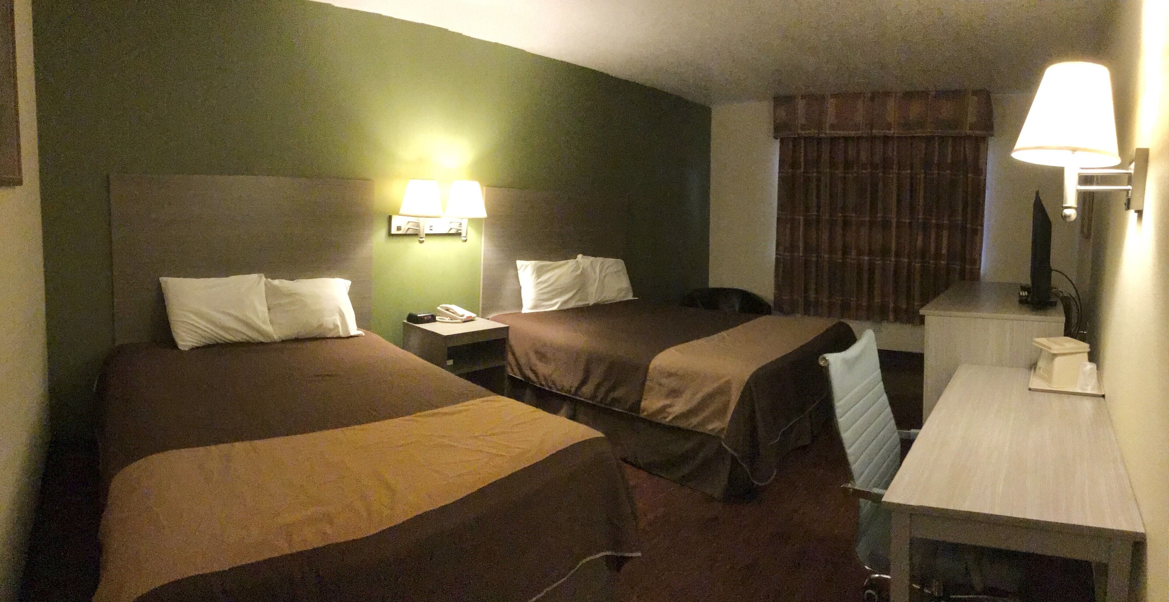 Ein Hotelzimmer mit zwei Betten, einem Schreibtisch, einem Stuhl, einem Telefon und einer Lampe.