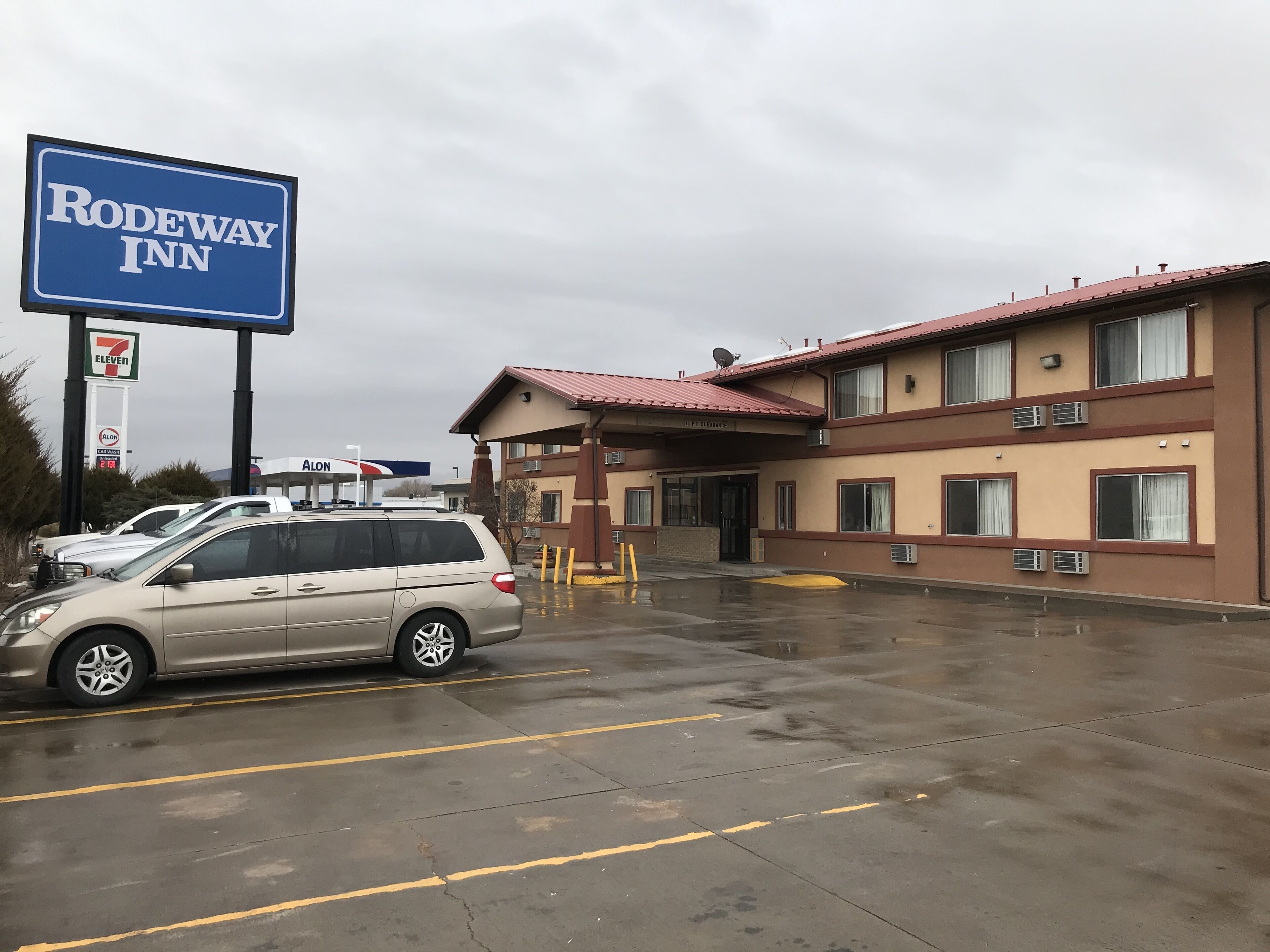 Un Rodeway Inn con una tienda 7-Eleven y una gasolinera Alon al fondo.