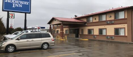 Un Rodeway Inn con una tienda 7-Eleven y una gasolinera Alon al fondo.