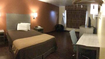Una habitación de hotel con cama, mesitas de noche, escritorio y silla.