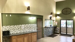 A kitchen with a tiled backsplash, wooden cabinets, and a microwave.