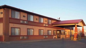 A two-story motel with a red roof and beige exterior walls.