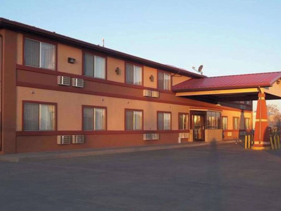 Un motel de dos pisos con techo rojo y paredes exteriores color beige.