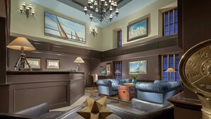 A lobby with a reception desk, seating area, chandeliers, and nautical-themed artwork. - Bristol Harbor Inn (BRISTOL)