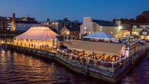 A waterfront restaurant with outdoor seating, a covered area, and a dock. - Bristol Harbor Inn (BRISTOL)